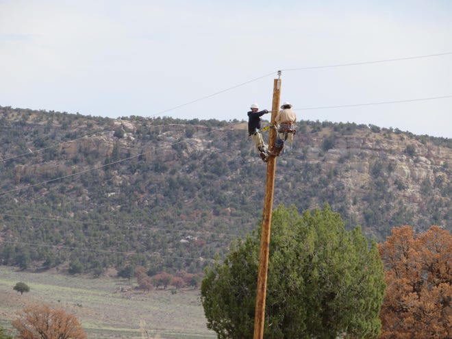 Workers install poles to bring electricity to remote parts of the Navajo Nation.  Broadband access is even worse.